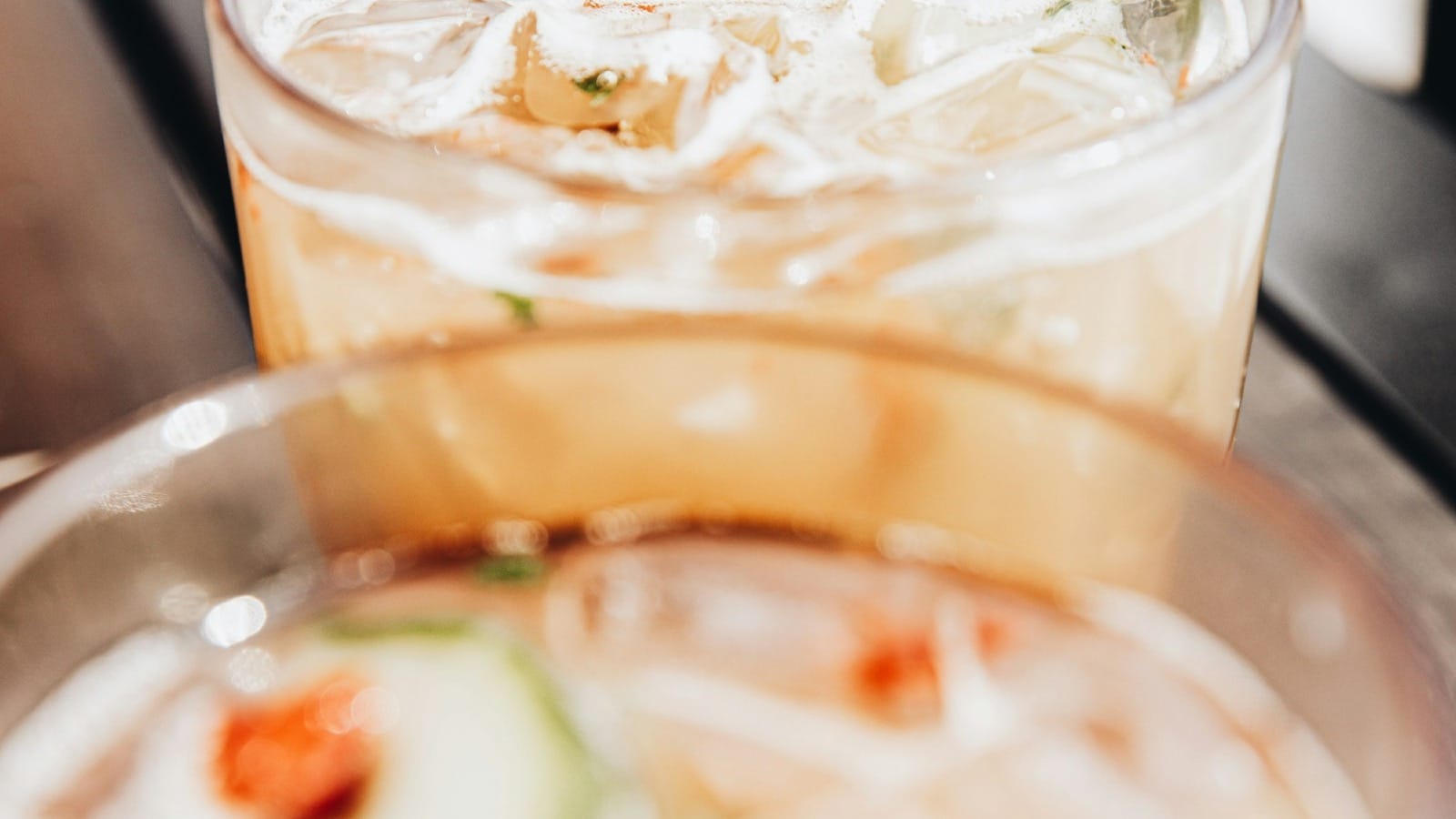 clear drinking glass with ice cubes and sliced of tomato