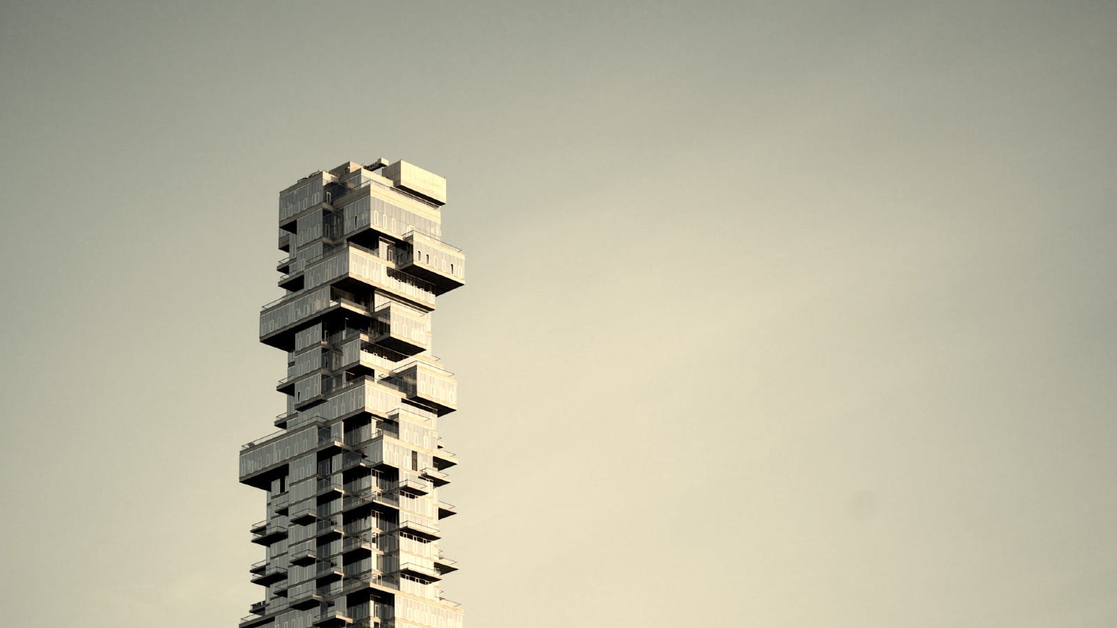 Staggered modular concrete blocks of a brutalist skyscraper against a desaturated sky. A metaphor for structural coherence in modular content architecture.