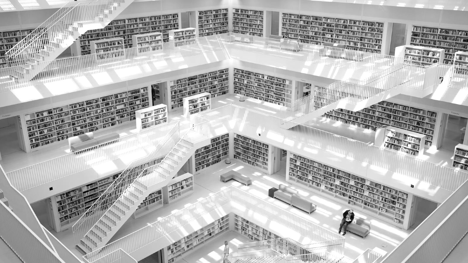 Minimalist white interior of a multi-level modern library with geometric stairs and bookshelves, symbolizing data architecture and the scale of the AI retrieval layer.