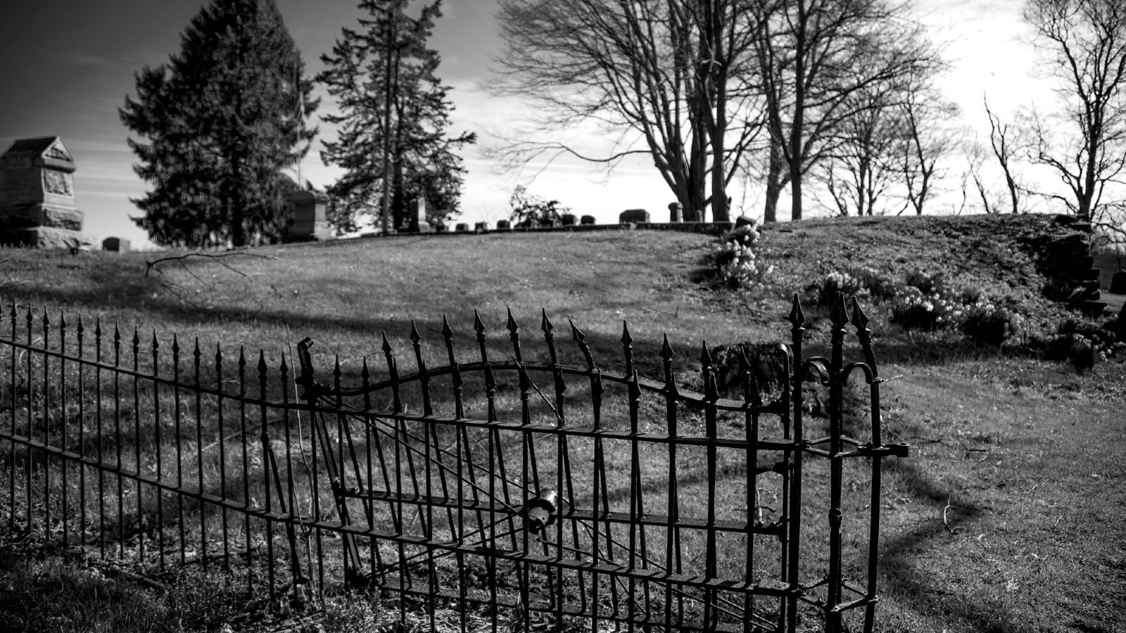 High-contrast black and white photograph of a graveyard behind a rusted iron fence, symbolizing the death of SEO clicks.