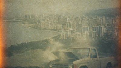A broken down truck with smoking radiator over looking downtown Honolulu symbolizing old broken SEO tactics against a modern backdrop. 