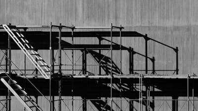 Industrial scaffolding and steel framework in black and white - representing the structural economics of marketing leadership for mid-market businesses