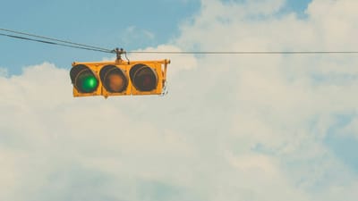 Traffic light with green signal lit, representing the choice between competing optimization signals on social platforms: velocity-based feeds versus intent-based search